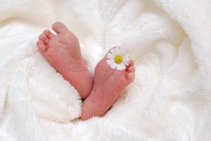 childs feet showing through soft blanket and a daisy